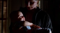 Scully's baby, William, is held by a disfigured, mysterious man